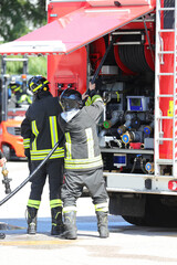firefighters grabbing the hose to extinguish the fire from the fire truck during a city emergency
