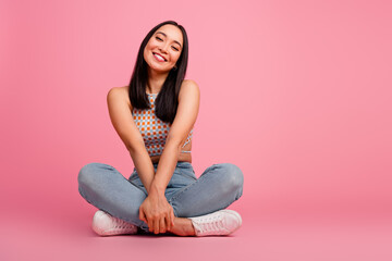 Young woman in trendy casual outfit smiling joyfully against pink background