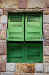 Old window in a stone house. Green window, against the background of stone walls