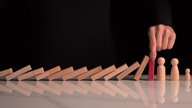 Falling dominos are stopped by a businesswoman&rsquo;s hand, symbolizing protection an