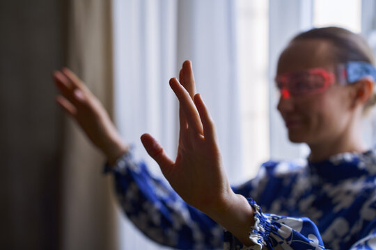 Woman wearing glowing glasses with raised hands in focus