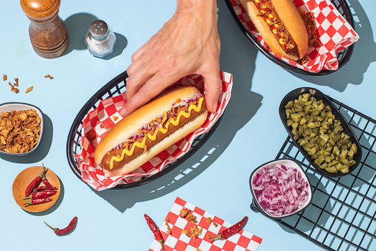 Hands Grabbing a Delicious Hot Dog