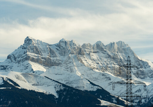 Majestic snowy mountains with towering power line in Switzerland