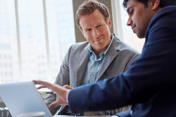 Laptop, website and men in office for conversation, advice or collaboration for business proposal. Consultant, financial advisor and businessman in meeting for project management, online idea or plan