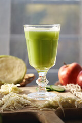 A cup of green cabbage and cucumber juice with fresh apples