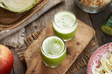 Two shot glasses of green cabbage juice with cucumber and apples