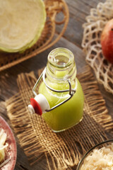 A bottle of green cabbage and cucumber juice with apples