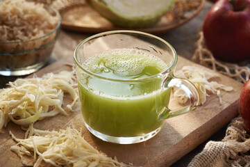 A cup of green cabbage and cucumber juice with apples