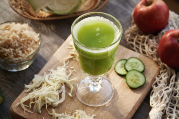 Fresh green cabbage and cucumber juice in a glass cup with red apples