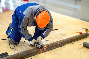 Industrial worker uses circular saw. Man with grinder is sawing steel pipe. Foreman with circular saw in work uniform. Employee of pipeline manufacturing company. Utility repair specialist