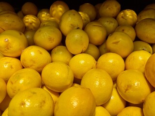 bright yellow lemons tangerines in a box in a supermarket on sale
