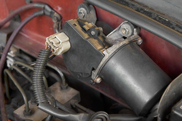 close-up of black windshield wiper motor of car, electric motor with gear mechanism with wiring...