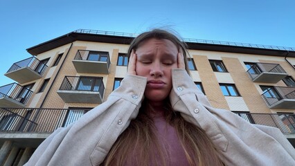 sad woman against the backdrop of an apartment building