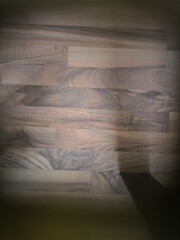 An abstract view of laminate seen through a glass coffee table, with light reflecting off the surface. The geometric shapes and textures create a visually intriguing, modern design.