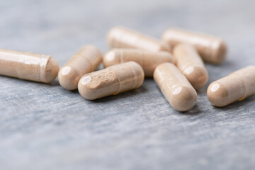 Reishi capsules. Concept for a healthy dietary supplementation. Wooden background. Soft focus. Close up.	