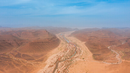 Moroccan Sahara Desert, ancient black volcanic mountains, the Sahara River Oued Ghris, stunning Acacia trees, wild camels, and desert camp,  landscape where golden sand dunes merge with green plants