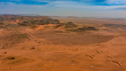 Moroccan Sahara Desert, ancient black volcanic mountains, the Sahara River Oued Ghris, stunning Acacia trees, wild camels, and desert camp,  landscape where golden sand dunes merge with green plants