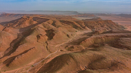 Moroccan Sahara Desert, ancient black volcanic mountains, the Sahara River Oued Ghris, stunning Acacia trees, wild camels, and desert camp,  landscape where golden sand dunes merge with green plants