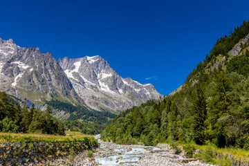 Val Ferret mountain landscape in the Alps. Tour du Mont Blanc beautiful scenic view from the hiking path on the way from Itlay to Switzerland. Alpine meadow and high snow peaks of the Alps on the sun