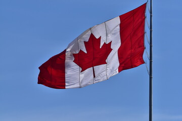 Canadian flag waving against blue sky