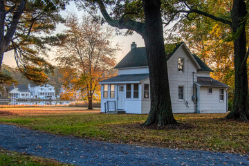 Old turn-of-the-century farmhouse surrounded by golden and orange autumn trees. 