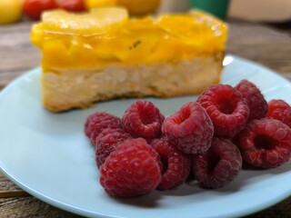 a cake with juicy raspberries lying next to it on a plate. High-quality photos