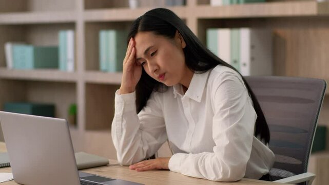 Unhealthy sick depressed sad Korean Asian businesswoman office worker Japanese manager secretary business woman female suffering headache pain tension migraine rubbing forehead problem deadline inside