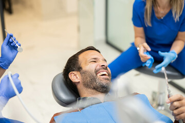 A male patient shares a light-hearted moment with dental professionals during his appointment,...