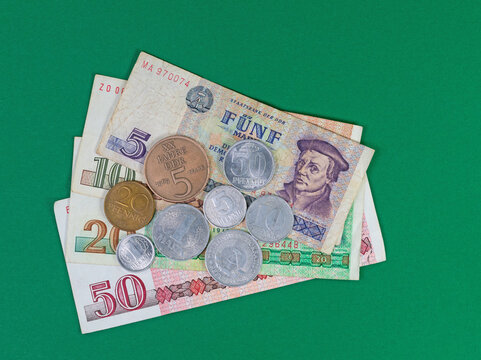 DDR-Geld, M&uuml;nzen und Geldscheine vor gr&uuml;nem Hintergrund