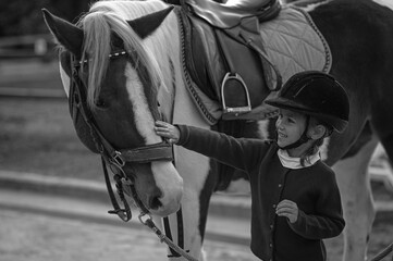 Young girl riding a horse in a traditional stable, embodying the classic bond between rider and...