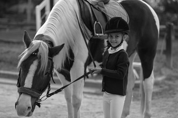 Obraz premium Young girl riding a horse in a traditional stable, embodying the classic bond between rider and steed