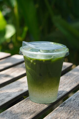 front view ice and cool matcha green tea in a plastic cup on table, on nature background, drink, japan , fashion, object, health, copy space