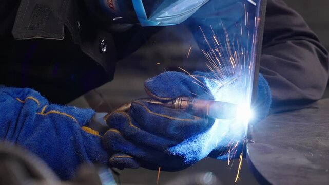 Masterful Welding in Action A skilled technician clad in protective gear creates a dazzling display of sparks and light while meticulously joining metal in this high-quality, 4K video.