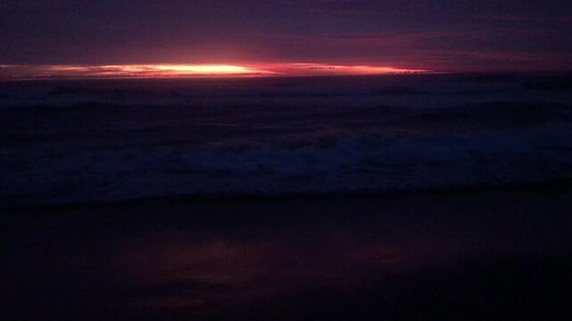 The sun sets over a calm beach, gentle waves wash over the shore. Golden times are on the horizon.