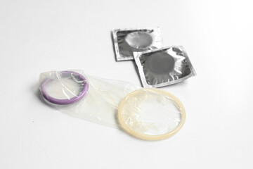 Open and wrapped condoms on white background