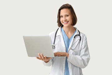 Beautiful female doctor with modern laptop on white background