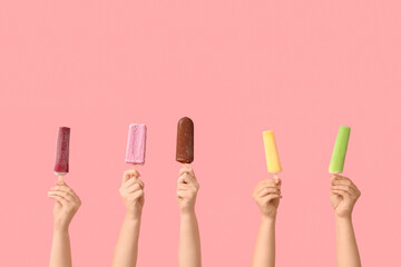 Female hands with different sweet ice-cream on pink background