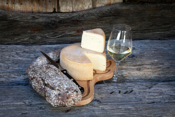 planchette apéritive avec une tomme du Valais, un verre de vin blanc, une saucisse d'Hérens, un pain de seigle