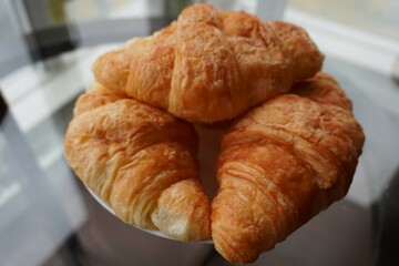 Three French croissants on the glass table