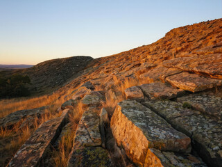 Naturally cracked rocky terrain illuminated by evening sunlight, showcasing rough textures and earthy tones. A serene landscape evoking natural beauty. Generative AI