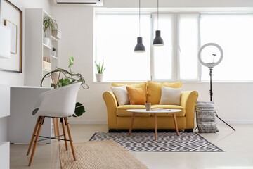 Interior of podcaster's studio with sofa, workplace and shelf unit