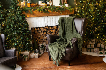 Fireplace room with Christmas decor. Classic armchairs, Christmas tree and fireplace