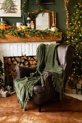 Fireplace room with Christmas decor. Classic armchairs, Christmas tree and fireplace