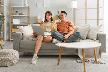 Young couple using laptop on sofa at home