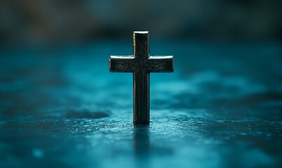 A single metal cross stands in focus against a blurred dark blue background, symbolizing faith, spirituality, and religious devotion.