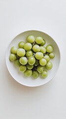 きれいな背景に白いボウルに並べられた新鮮な緑のブドウ