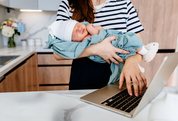 Mother multitasking with baby in modern kitchen setting
