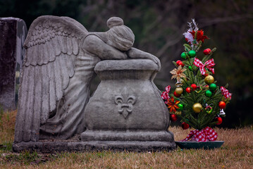 Christmas tree and weeping angel in cemetery, concept of holiday grief and sad holidays