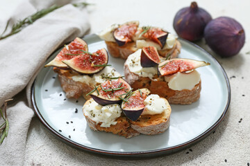 Plate of delicious fig bruschetta with ricotta cheese and rosemary on white background