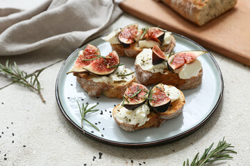 Plate of delicious fig bruschetta with ricotta cheese and rosemary on white background, closeup